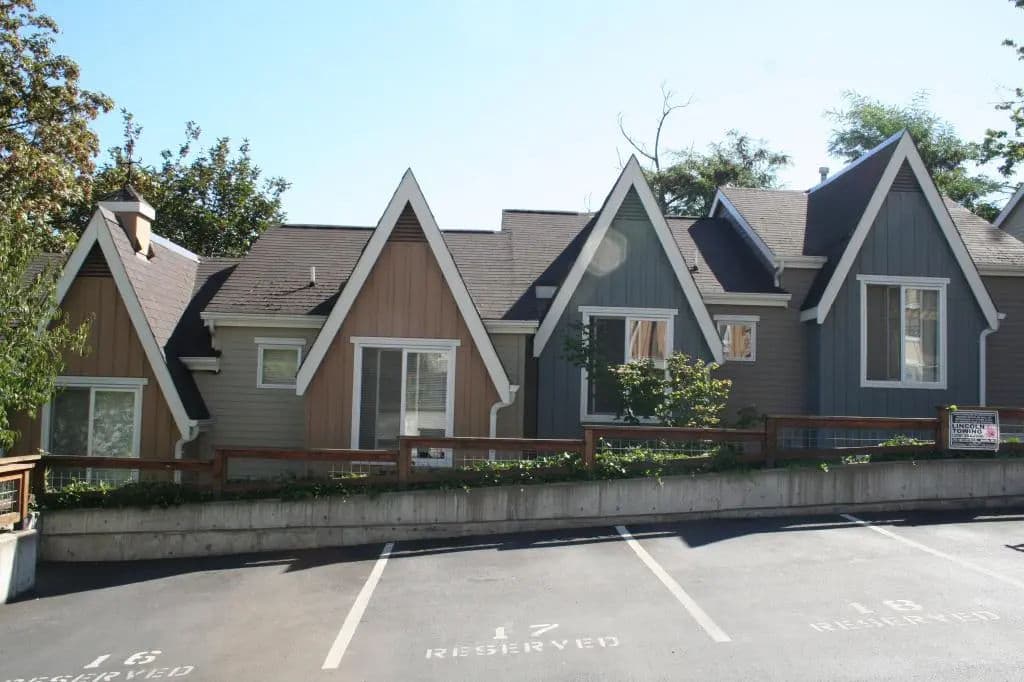 Charming multi-colored duplex with triangular roofs and parking spaces in front.
