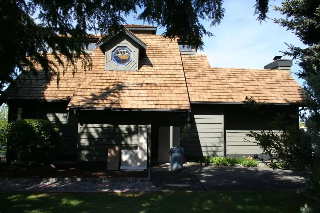 Charming house with a shingled roof, decorative window, and landscaped surroundings.